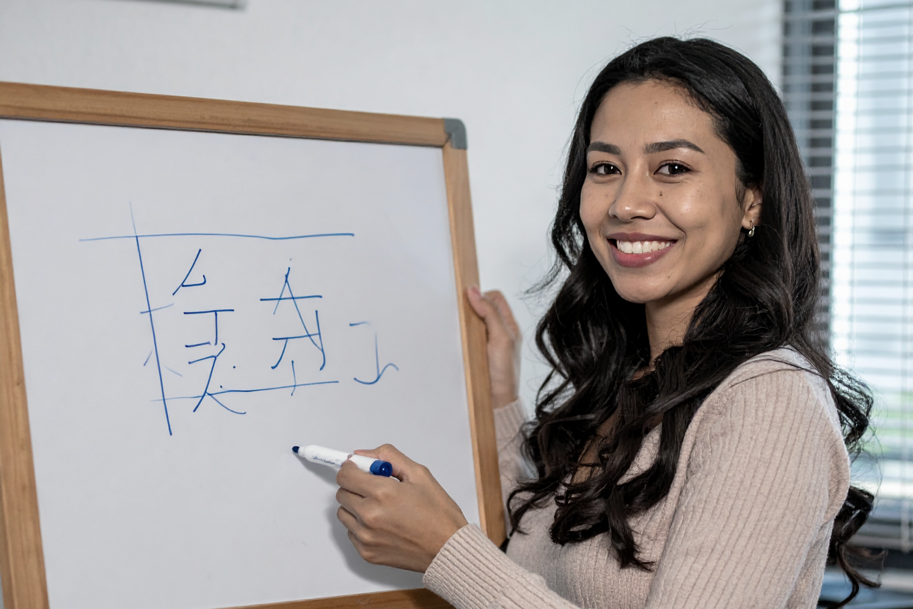 Language tutor in front of whiteboard writing Chinese characters during an authentic immersion class